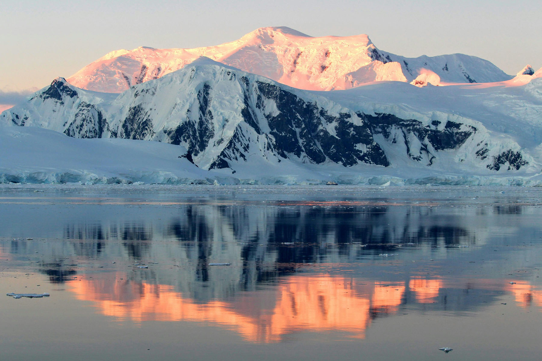 Sun shinning on snow covered peaks by the sea